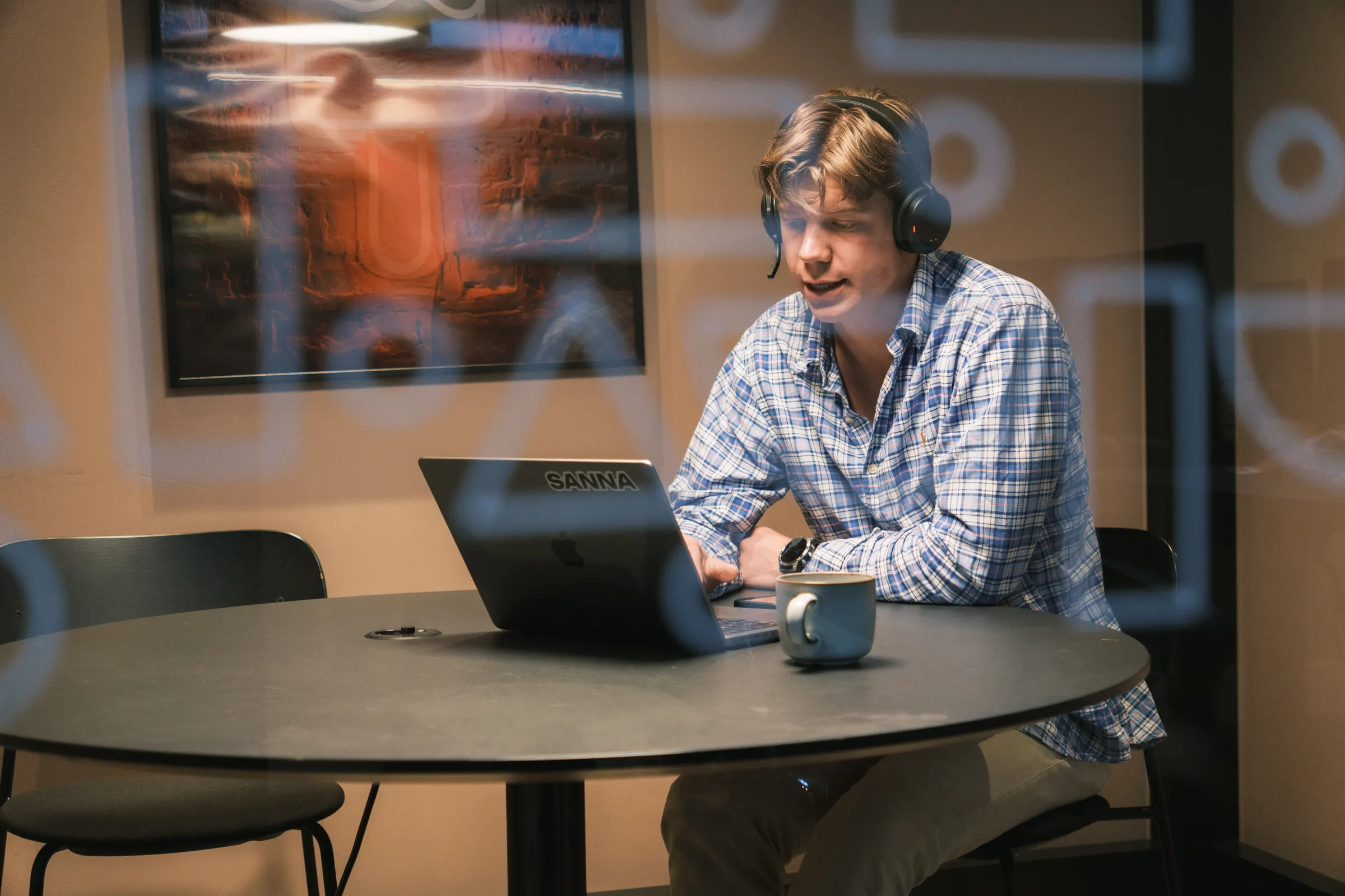 Medarbetare med headset vid laptopen i ett mötesrum med glasväggar